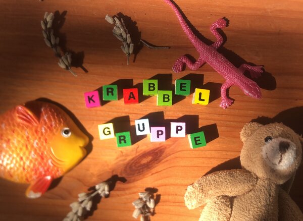 Bild vergr&ouml;&szlig;ern: Krabbelgruppe in bunten Buchstaben mit Spielzeug.
