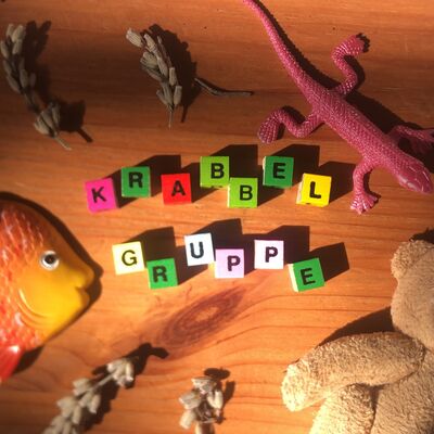Krabbelgruppe in bunten Buchstaben mit Spielzeug.